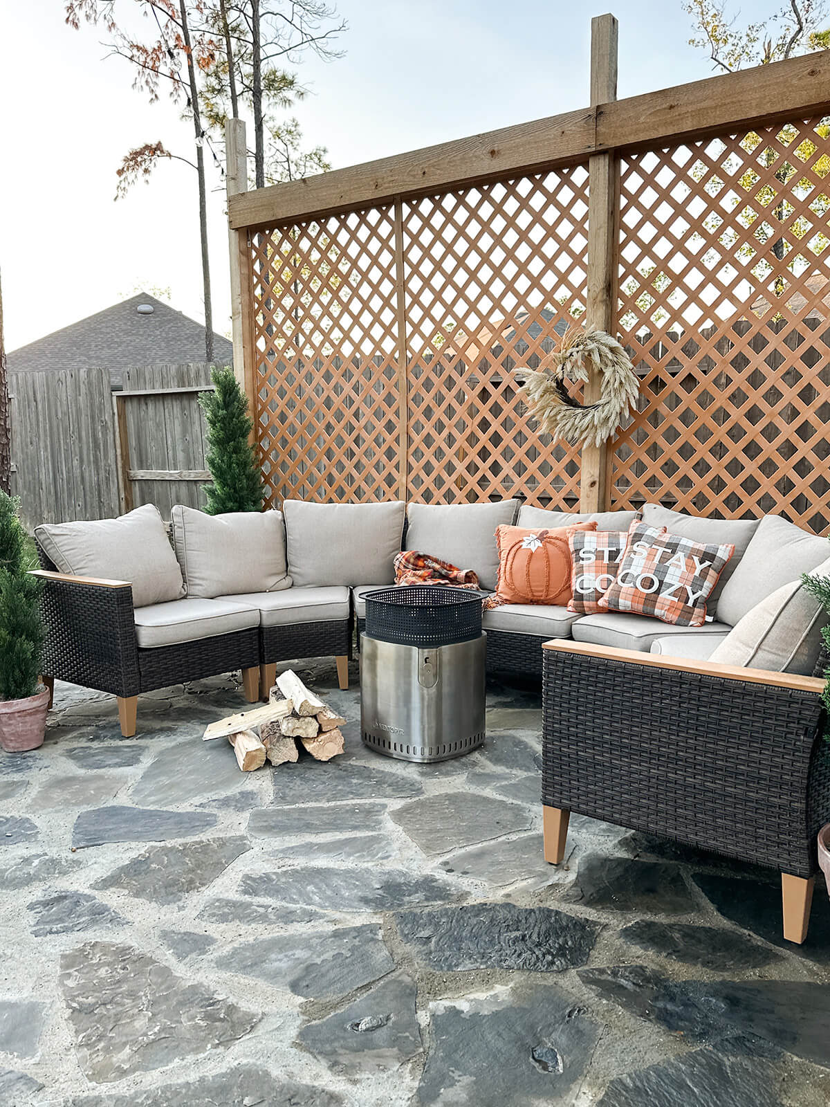 A smokeless fire pit and a pile of firewood are placed next to an outdoor sofa