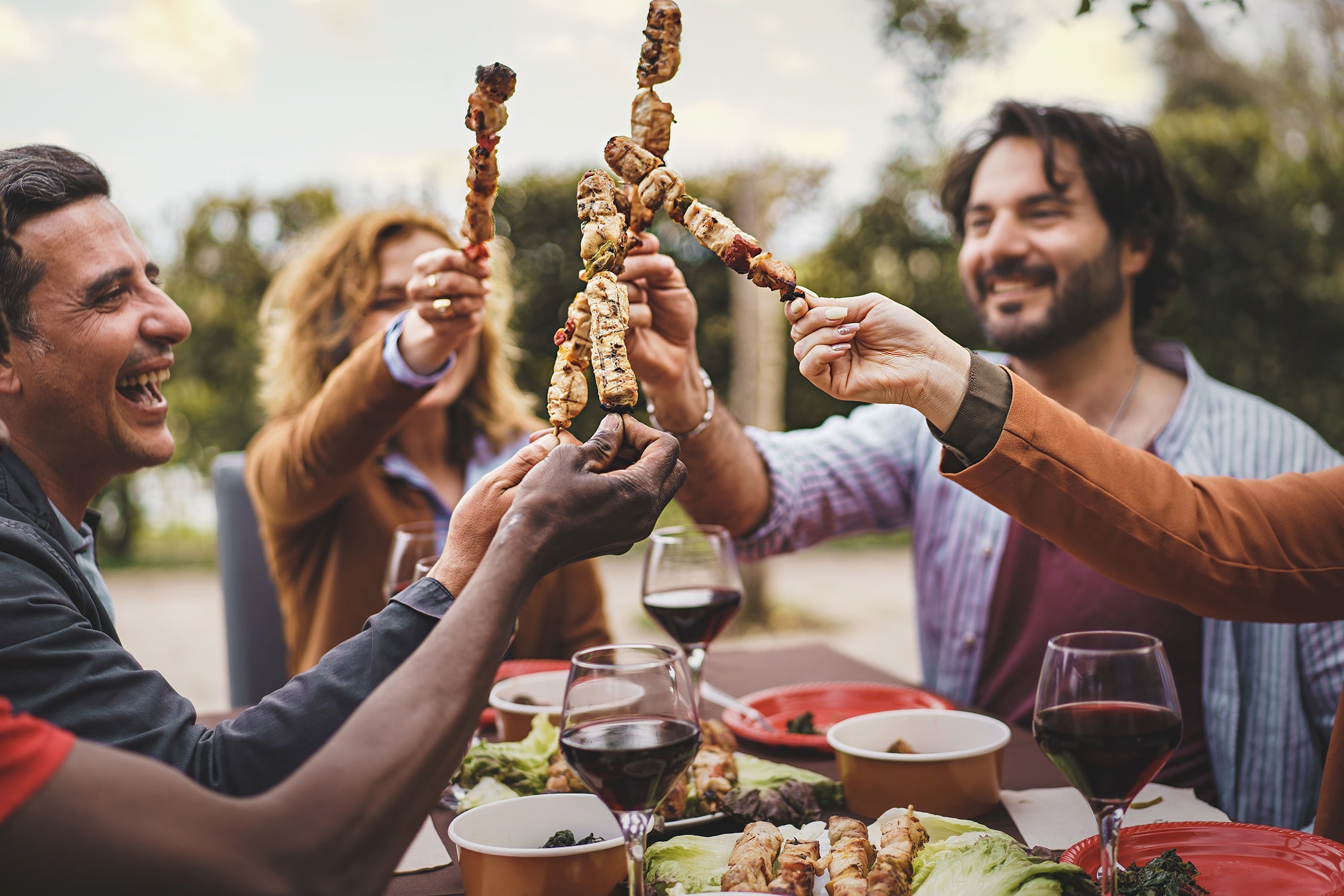 A group of people laughing while holding skewers